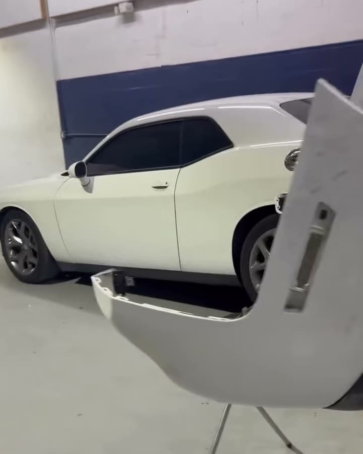 A white Challenger bumper cover off the car and set on a stand